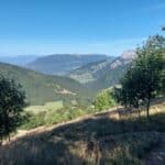 Paysage de marche en fillière avec vue sur collines verdoyantes et sentier nature.